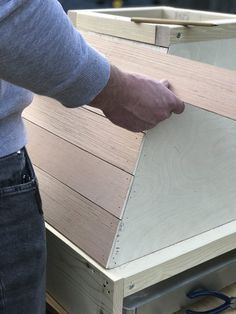 a man is working on some wood with plywood and scissors in his left hand