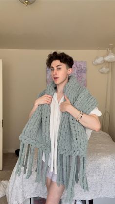 a woman standing in front of a bed wearing a shawl