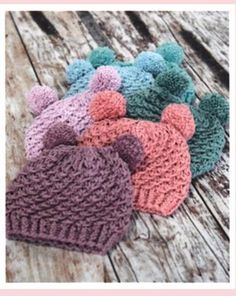 several knitted hats sitting on top of a wooden table