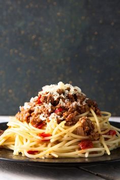 spaghetti with meat and sauce on a black plate