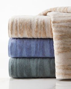 four folded towels stacked on top of each other in various colors and patterns, all with different textures