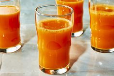 three glasses filled with orange juice on top of a table