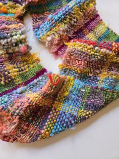 a multicolored knitted scarf laying on top of a table