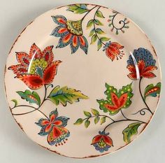 a white plate with colorful flowers and leaves painted on the side, holding two spoons