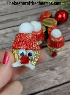 a hand holding a small santa clause ornament with red and gold decorations on it