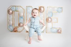 a baby is sitting on a chair in front of balloons and letters that spell it's 1st birthday