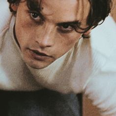 a close up of a person wearing a sweater and looking at the camera with a serious look on his face