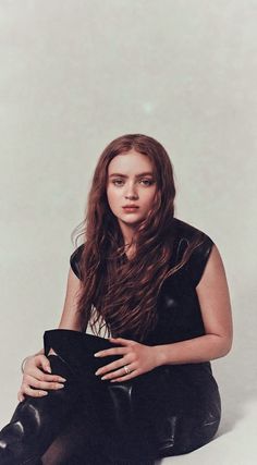 a woman sitting on the floor with her legs crossed and wearing black leather pants,