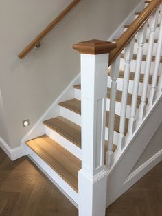 a white staircase with wooden handrails and wood flooring