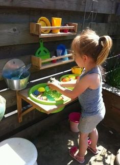 a colorful outdoor kitchen with wooden shelves, colorful plastic tableware and toys for having fun Kids Play Spaces, Play Garden, Outdoor Play Areas, Outdoor Play Area, Play Spaces