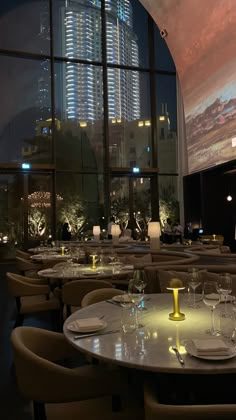 an empty restaurant with tables and chairs in front of a large window at night time