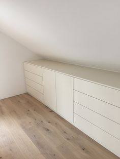 an empty room with wooden floors and white cabinets on the wall, along with hard wood flooring