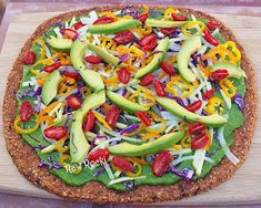 a pizza topped with lots of veggies on top of a wooden cutting board