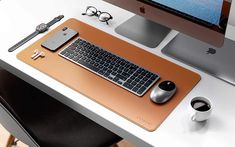 a computer desk with a keyboard, mouse and cell phone on it in front of a monitor