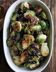 a white bowl filled with brussel sprouts on top of a wooden table