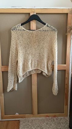 a white sweater hanging on a wooden hanger