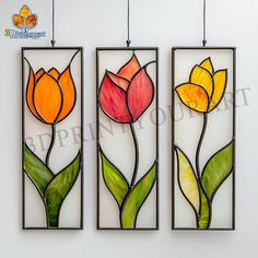 three stained glass panels with flowers hanging from the ceiling in front of a white wall