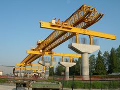 a large yellow crane sitting on top of a cement block in the middle of a construction area