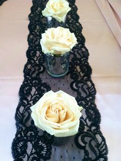 two vases with roses are sitting on a lace table runner that's lined up