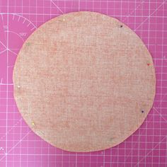 a round piece of fabric sitting on top of a cutting board next to a ruler