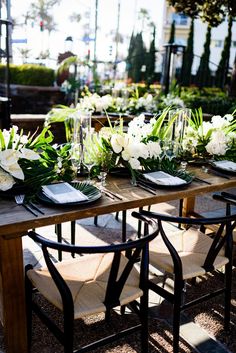 an outdoor table set with place settings and flowers