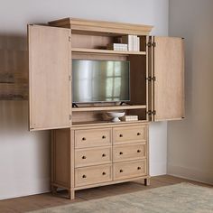 a wooden entertainment center with drawers and a television on it's side, in front of a white wall