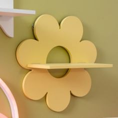 a flower shaped shelf mounted to the side of a wall next to a pink chair