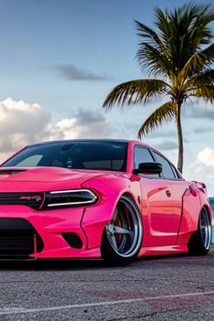 a pink car parked next to a palm tree