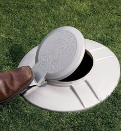 a close up of a person's foot near a white object on the grass