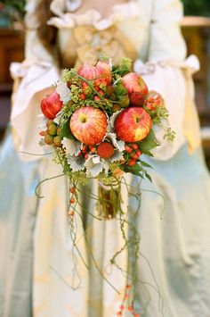 a bride holding a bouquet of apples in her hand