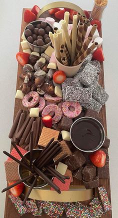 a wooden table topped with lots of different types of candies and donuts on top of each other