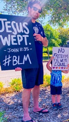 a man holding a sign next to a little boy