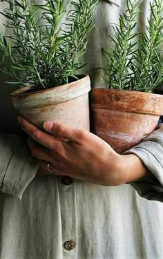 a woman holding two potted plants in her hands