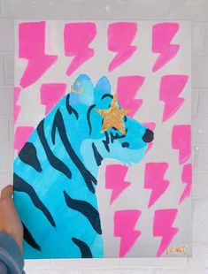 a person holding up a painting with a zebra on it's face and lightning bolt in the background