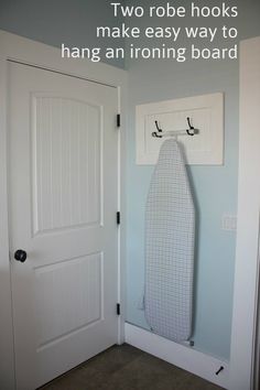 an ironing board is hanging on the wall in front of a door with hooks