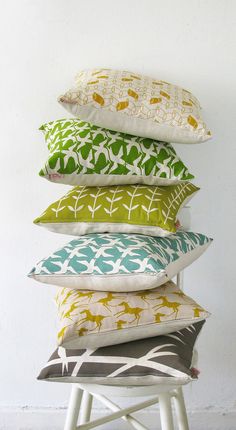 a stack of four pillows sitting on top of a white stool next to a wall