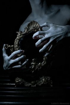 two hands holding a mirror in the dark