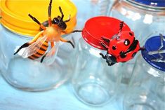 three plastic ladybugs sitting on top of each other in front of glass jars