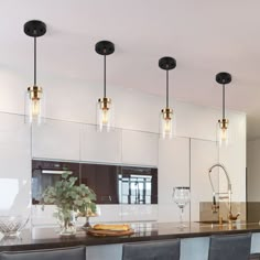 a kitchen with four lights hanging from the ceiling and bar stools in front of it