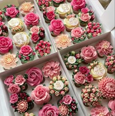 four boxes filled with cupcakes covered in pink and white frosting flowers on top of each one