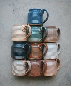 a stack of coffee mugs sitting next to each other on top of a cement floor