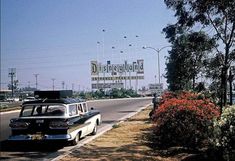 an old car is parked on the side of the road in front of a sign