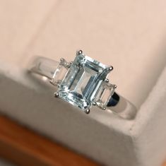 an emerald cut diamond ring sitting on top of a box