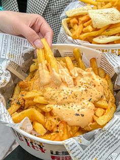 a person is holding a hot dog and french fries in a paper basket with ketchup on top