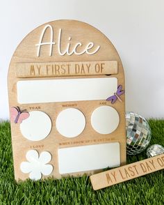 a wooden plaque with the words alice my first day of school on it next to some golf balls