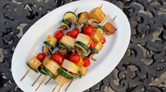 a white plate topped with veggies and tofu on skewered sticks