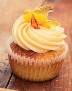 a cupcake with white frosting and a garnish on top is sitting on a wooden table