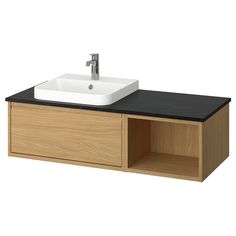 a bathroom sink with a black counter top and wooden cabinet underneath the faucet