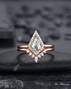 an engagement ring with a pear shaped diamond surrounded by small diamonds on top of a rock