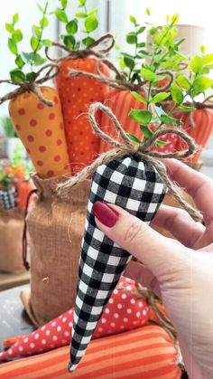 a hand holding an object in front of some potted plants and other decorative items